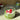 A glass cup filled with layered matcha chia pudding and yogurt, topped with three fresh raspberries. A tin of organic matcha powder sits in the background on a sunlit counter