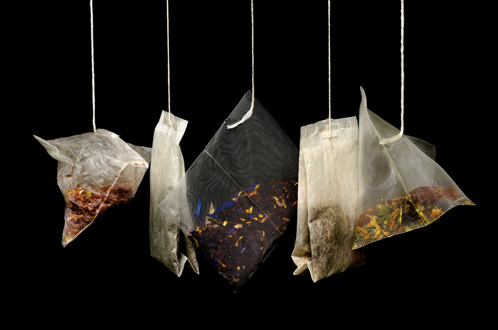 A photo of 5 hanging tea bags on a dark background